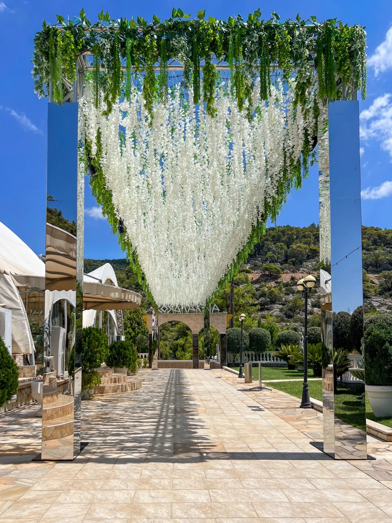 Στολισμένη αψίδα με λευκές γιρλάντες βιστέριας στον εξωτερικό χώρο